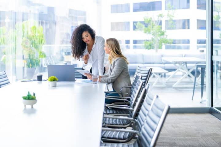 Business colleagues having a conversation in a board room. They are both young business people casually dressed in a modern office